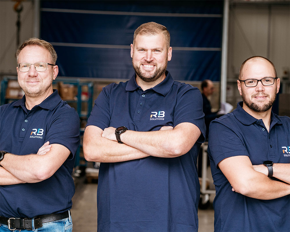 Drei Mitarbeiter von RB Solutions in der Werkhalle Drei Mitarbeiter von RB Solutions in der Werkhalle
